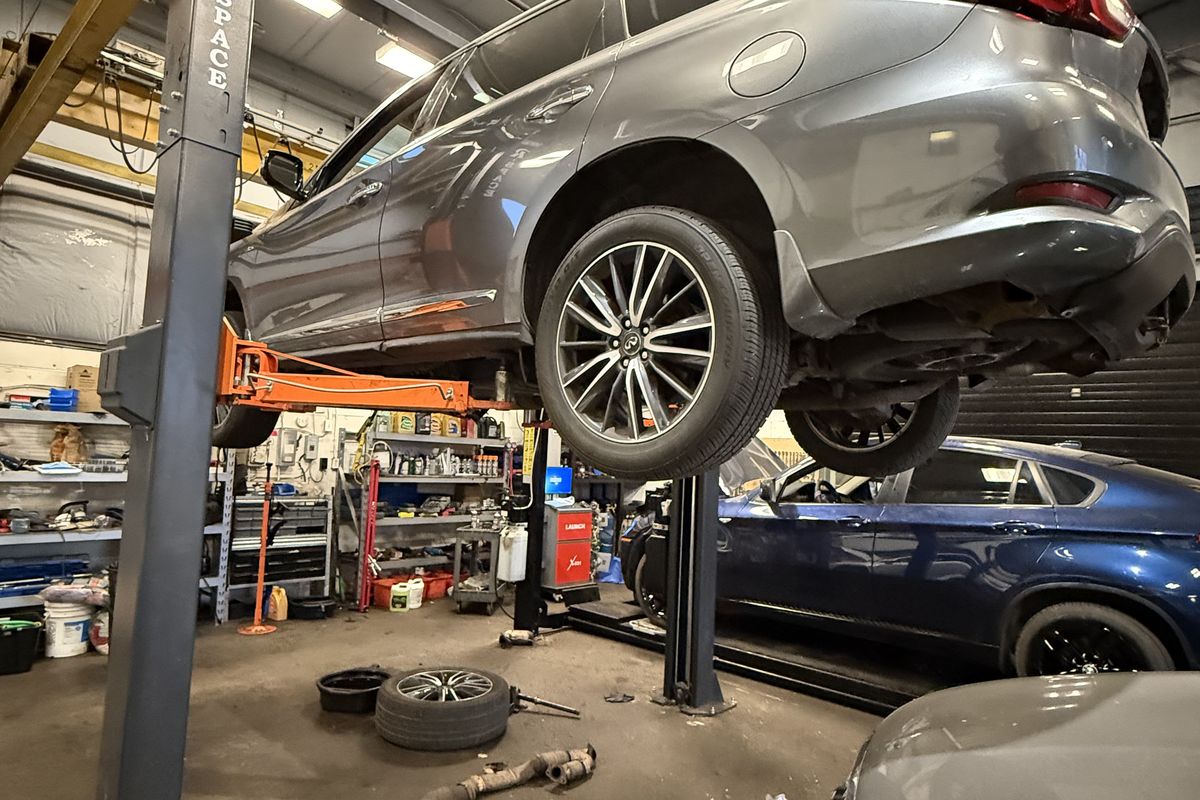 Vehicle raised on the two-post hoist with a wheel removed for suspension work